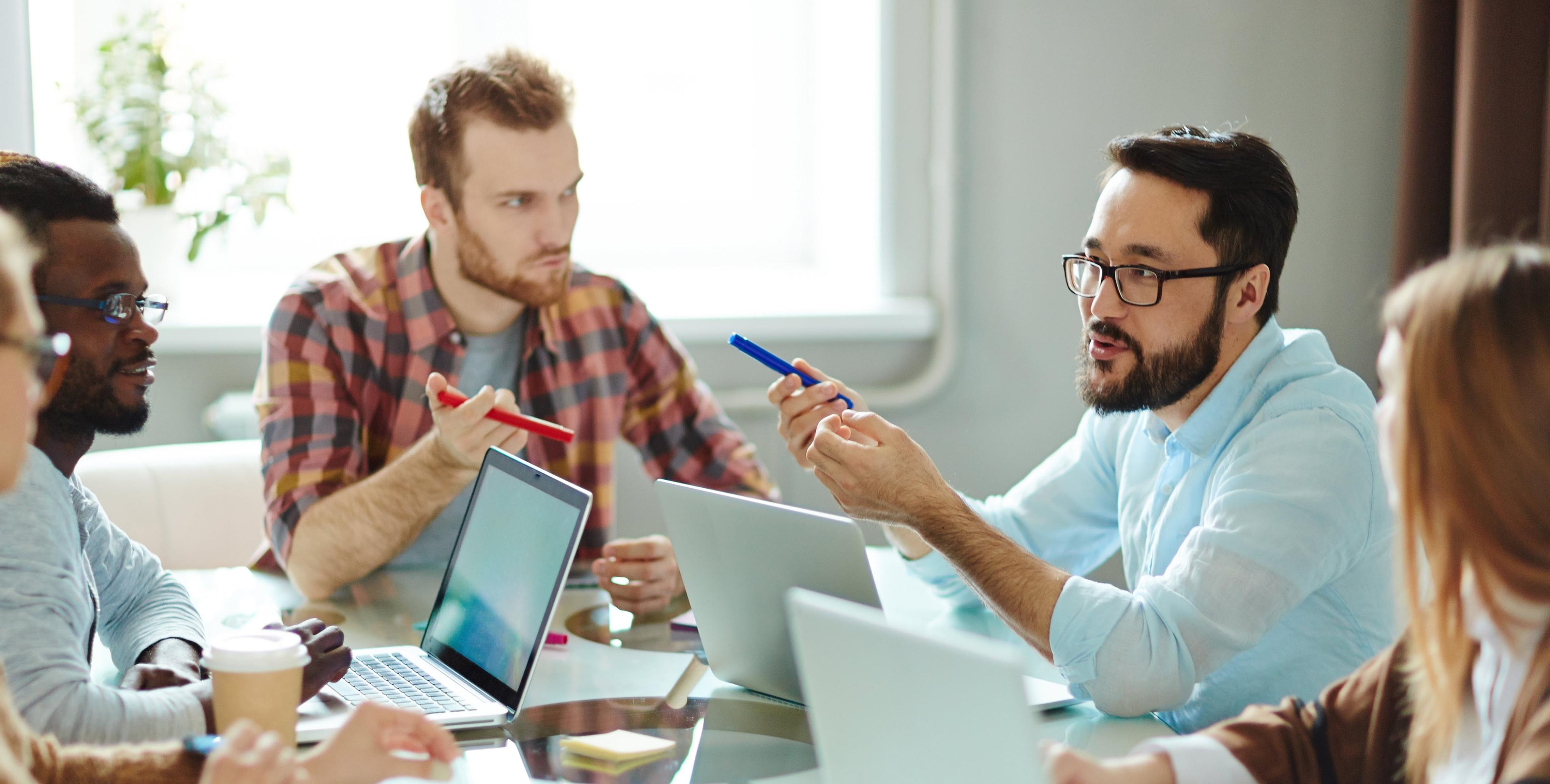 A group of young professionals sit in a meeting room discussing business ideas.